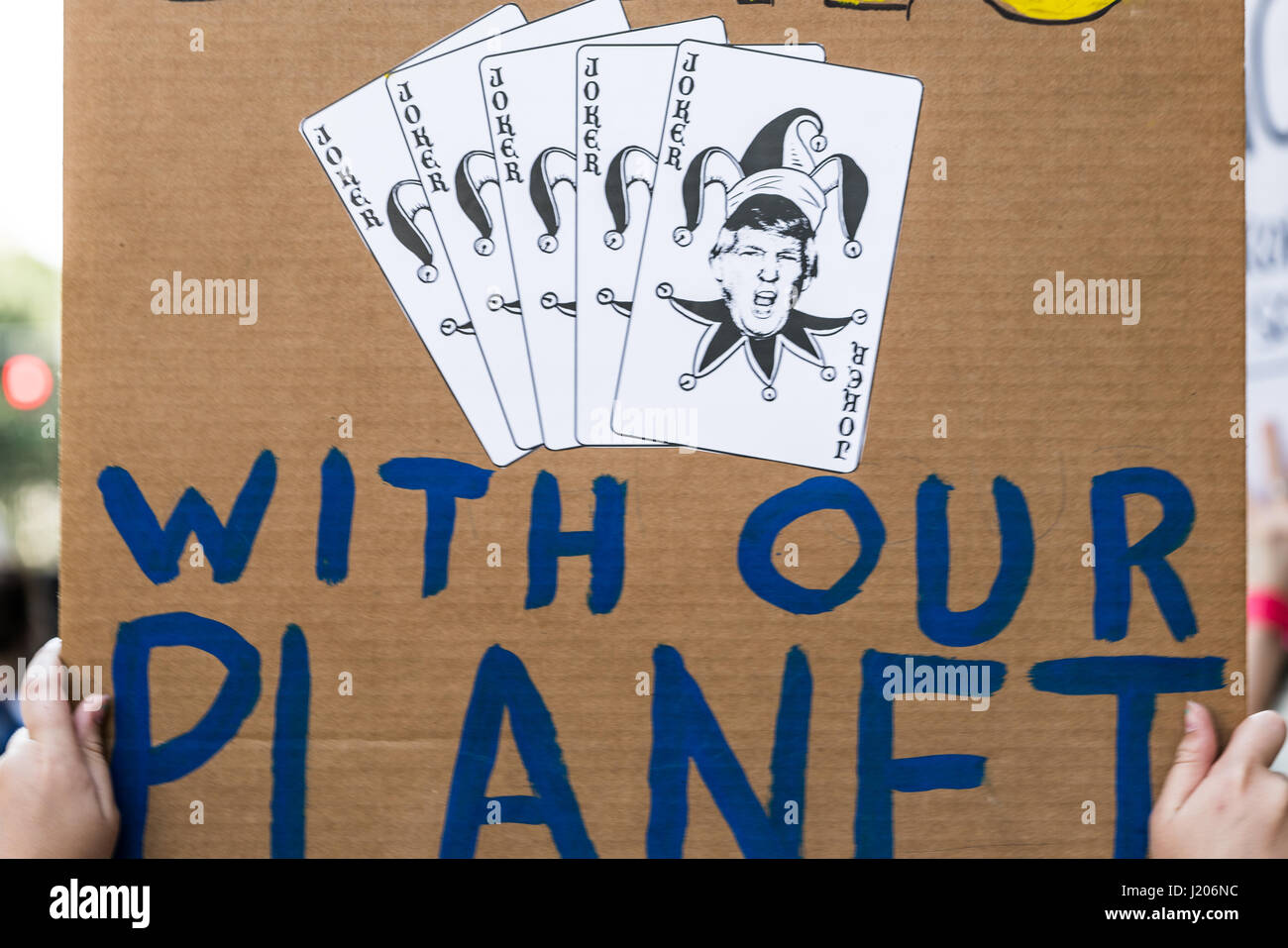 A protester holds a sign with Donald Trump's face on Joker cards that reads, 'Don't play games with our planet'. Stock Photo