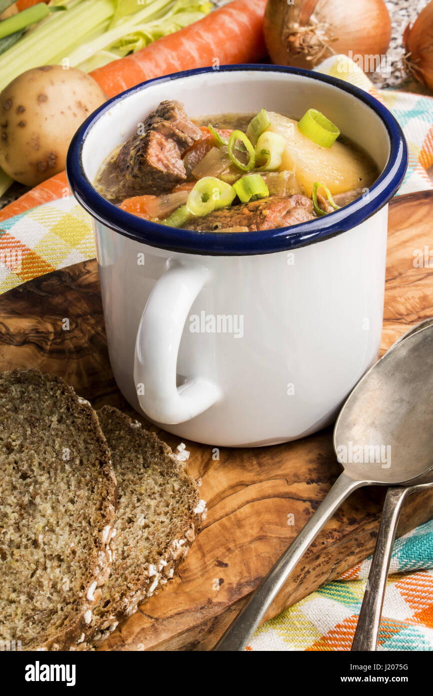 home made traditional irish lamb stew with potato, carrot, celery and spring onion in an white enamal cup Stock Photo