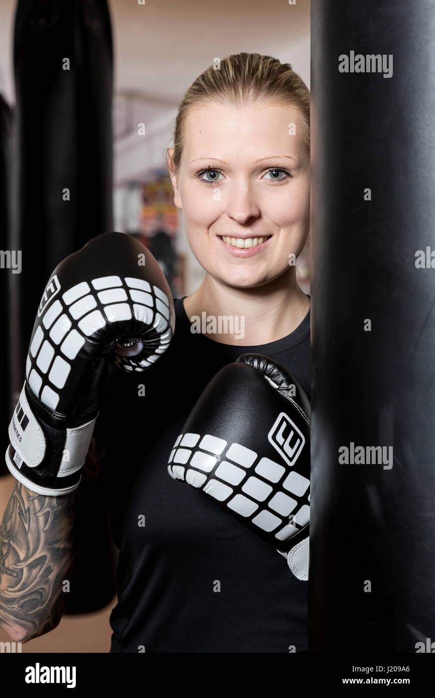 Young woman, tattooed, boxing at a sandsack in a boxing studio, Bavaria, Germany Stock Photo