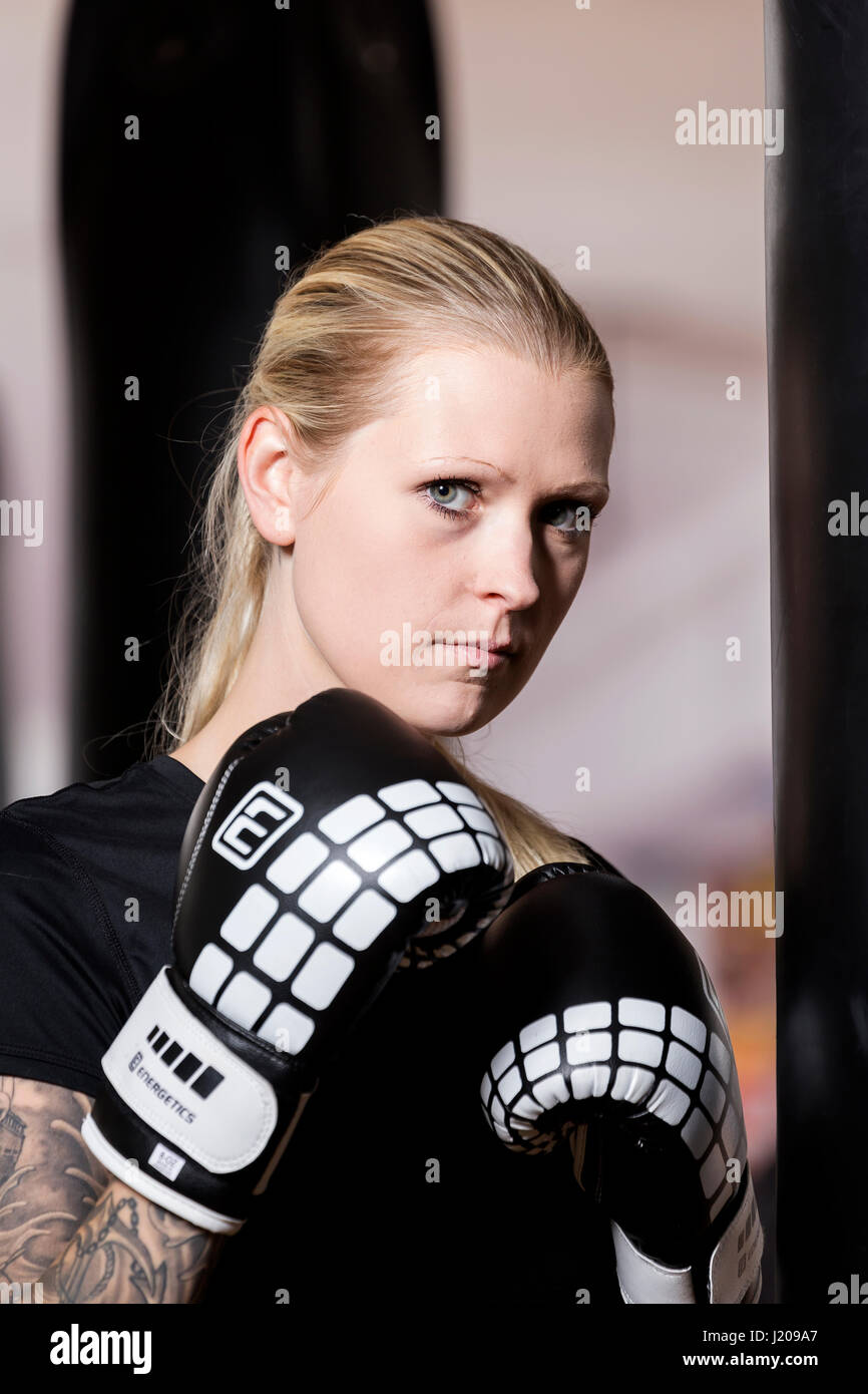 Young woman, tattooed, boxing at a sandsack in a boxing studio, Bavaria, Germany Stock Photo