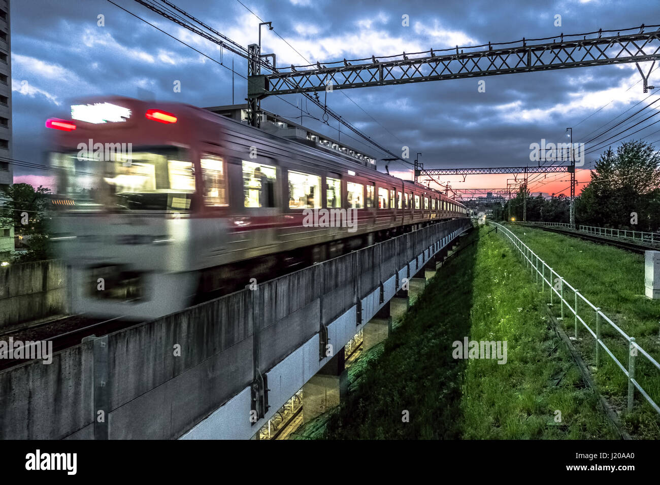 A train makes its way past a station in Tokyo at sunsettrav Stock Photo