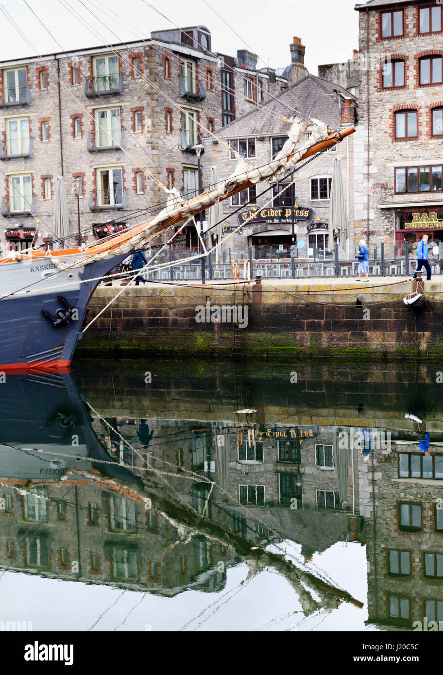 Prow of the tall ship, S.V.Kaskelot, reflected in the water of Sutton Harbour, Plymouth, UK, April 2017.  Part of the Barbican behind. Stock Photo