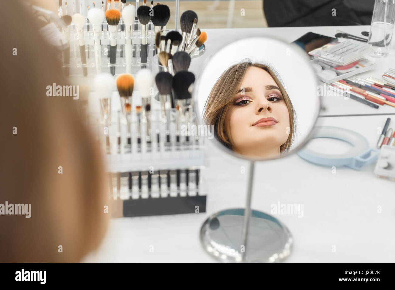 reflection in the mirror girl with glamorous makeup in beauty salon. Backstage photo. Beautiful