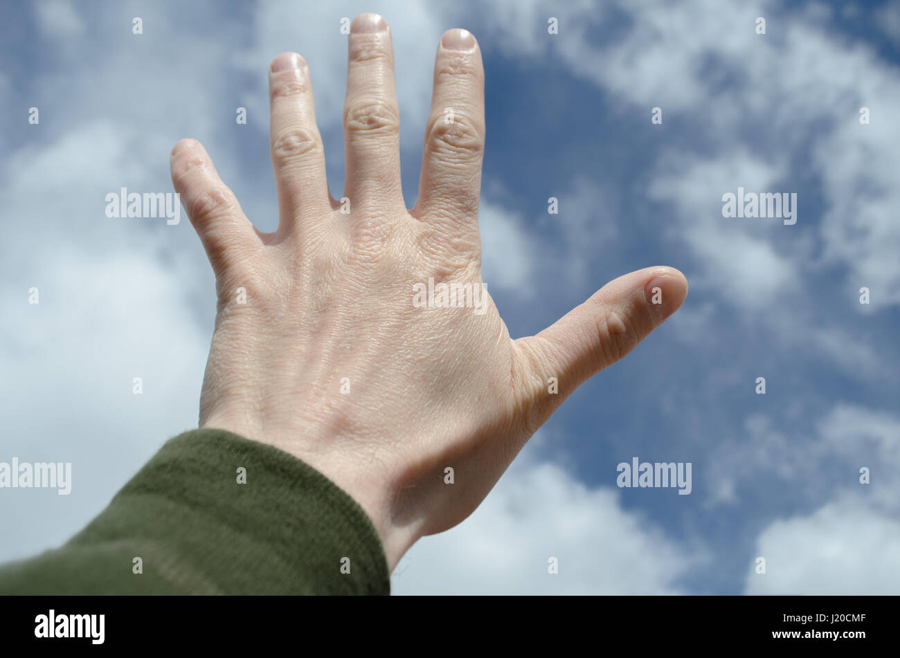 Hand doing stop gesture against blue sky Stock Photo