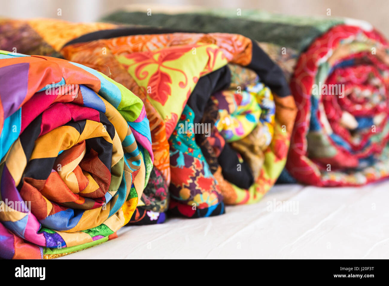 Three colored patchwork quilts twisted into close up. Colorful scrappy ...