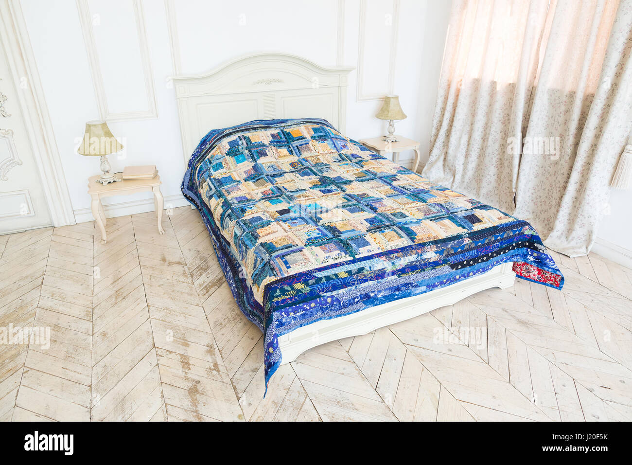 large bright double bed with a colored patchwork quilt in the white ...