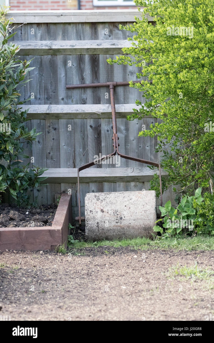 Old Heavy Lawn Roller leaning against a garden fence Stock Photo