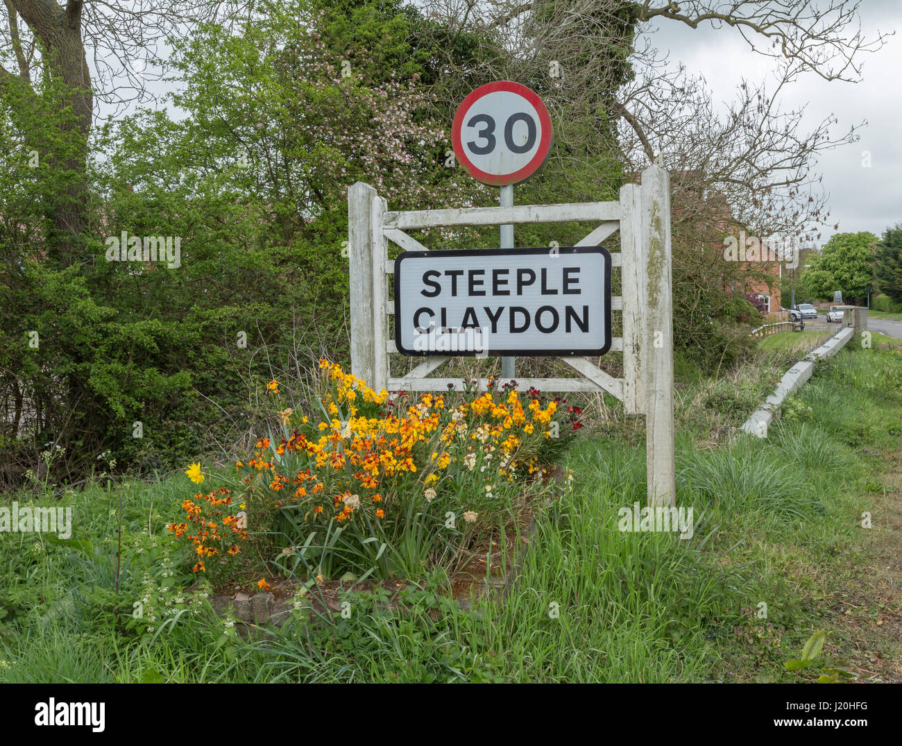 A steeple Claydon sign before entering the village with spring flowers