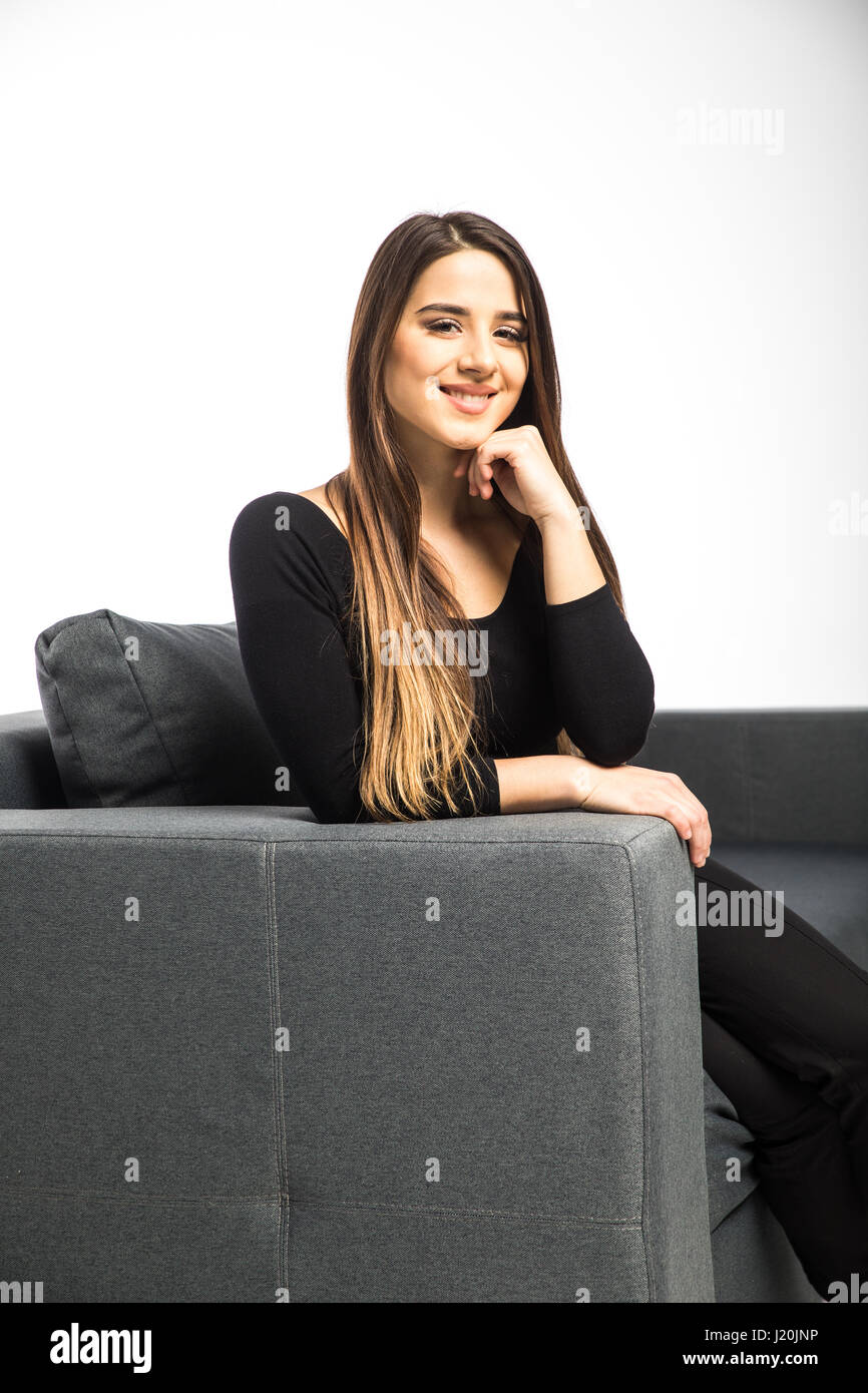 Portrait of happy young woman sitting on sofa Stock Photo - Alamy
