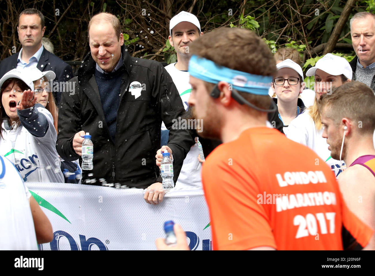 A runner squirts water as the Duke of Cambridge hands out water to runners during the 2017 Virgin Money London Marathon. Stock Photo