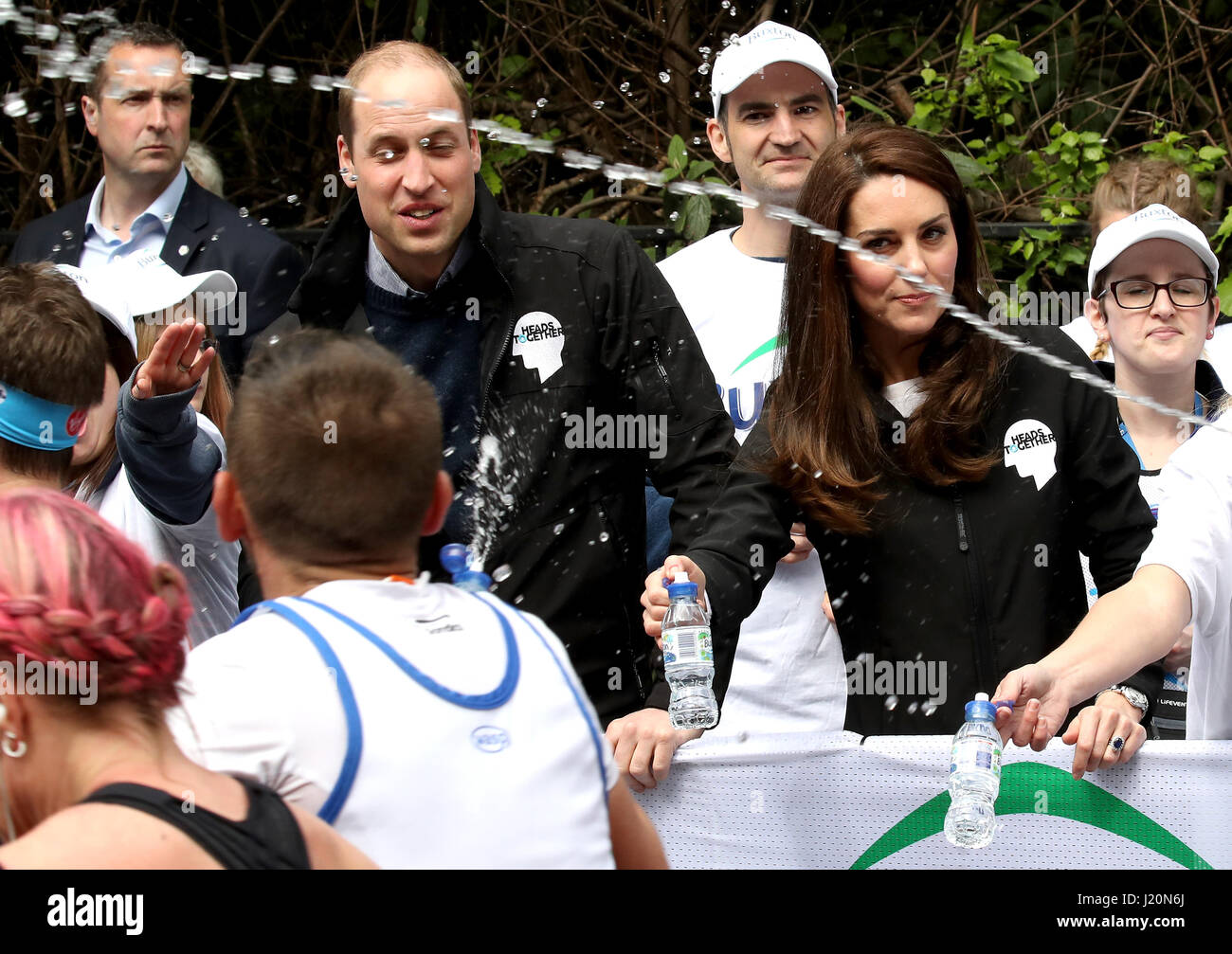 A runner squirts water as the Duke and Duchess of Cambridge hands out water to runners during the 2017 Virgin Money London Marathon. Stock Photo