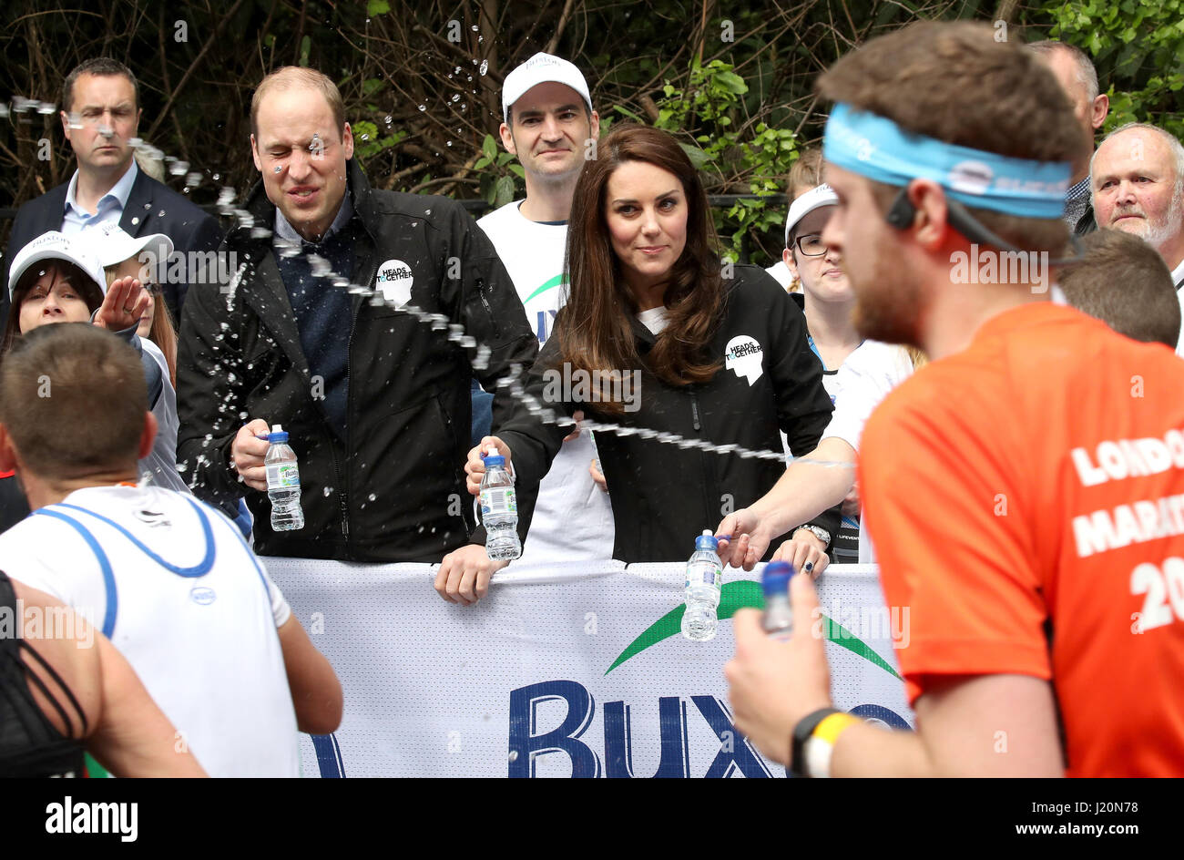 A runner squirts water as the Duke and Duchess of Cambridge hands out water to runners during the 2017 Virgin Money London Marathon. Stock Photo