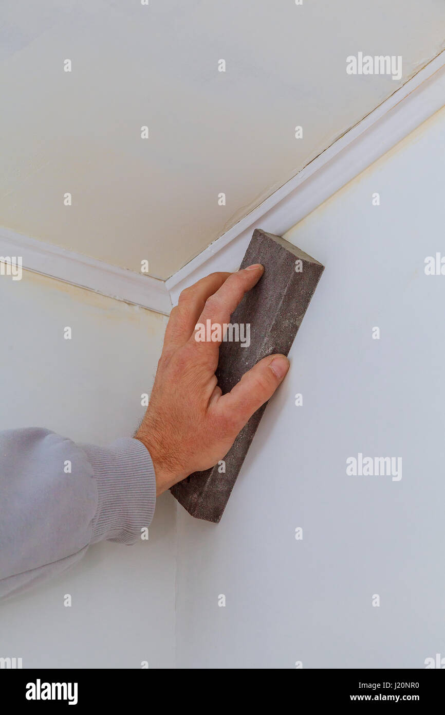 plastering man hand sanding the plaste in drywall seam plasterboard sanding  the wall Stock Photo - Alamy