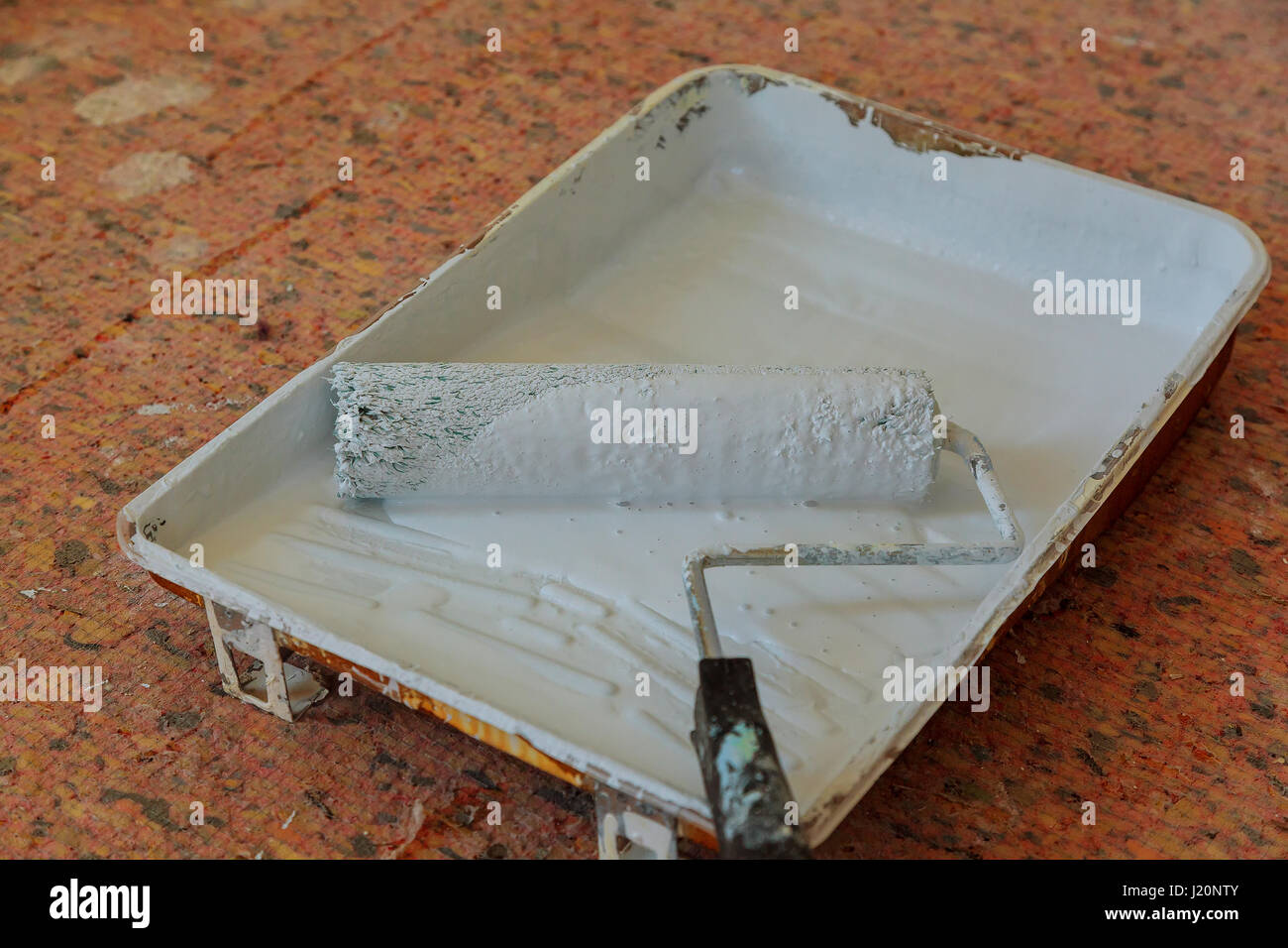 Roller painting,orange handle and black plastic tray on black plastic floor,background,painting
