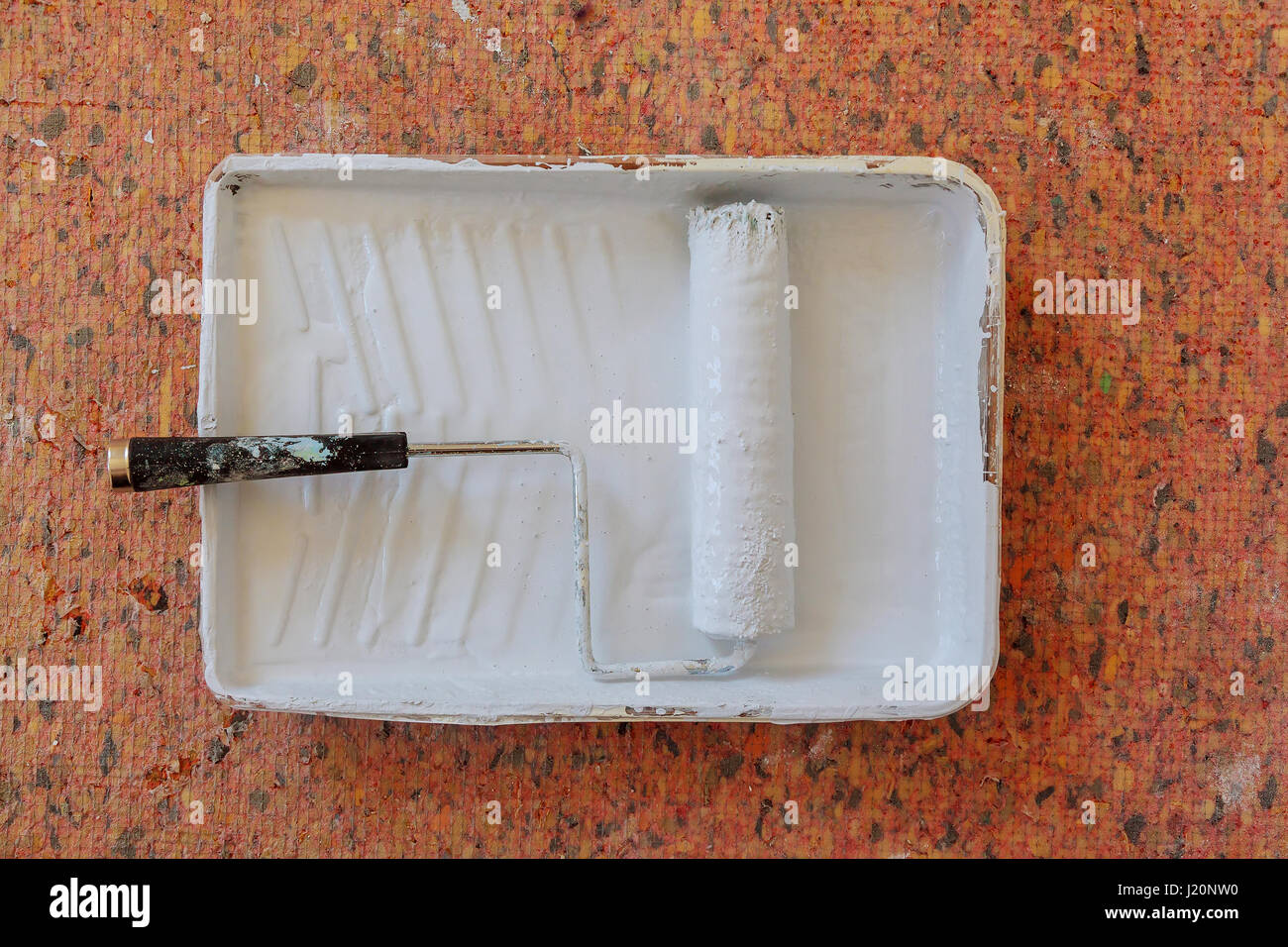 Realistic image of paint pan and roller on drop cloth during painting