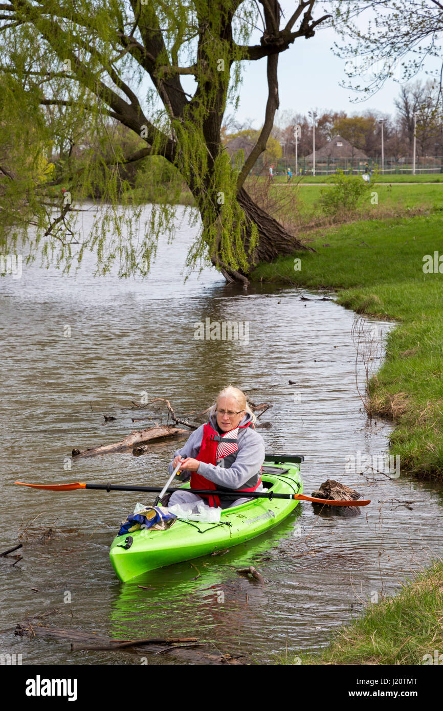 Detroit, Michigan - A volunteer in a kayak picks up trash during a spring cleanup of Belle Isle, a state park on an island in the Detroit River. Stock Photo