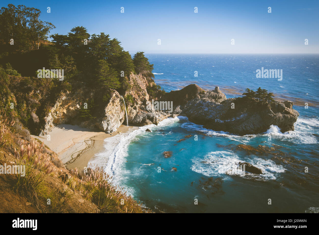 McWay Falls in golden evening light at sunset on a beautiful sunny day with blue sky in summer, Julia Pfeiffer Burns State Park, Big Sur, California Stock Photo