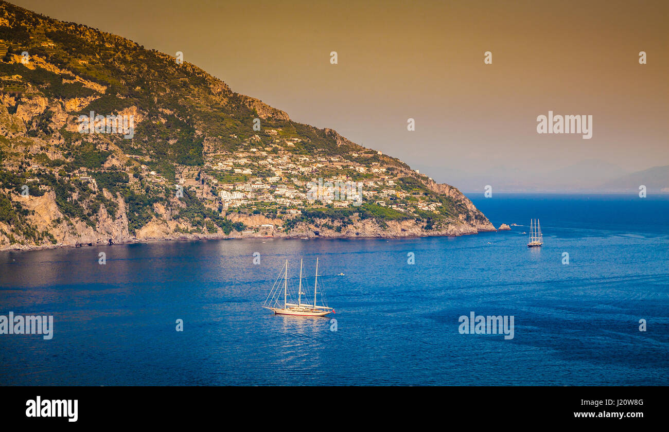 Panorama view of sailing yachts on the Mediterranean Sea at famous Amalfi Coast in beautiful golden evening light at sunset in summer, Campania, Italy Stock Photo