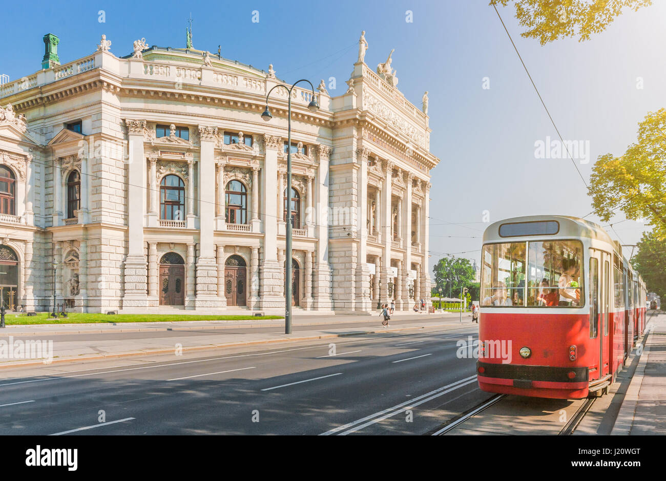 Classic view of famous Wiener Ringstrasse with historic Burgtheater and traditional red electric tram on a beautiful sunny day in Vienna, Austria Stock Photo