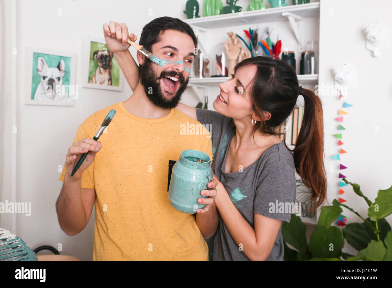 Young woman painting her boyfriend's face with paintbrush Stock Photo