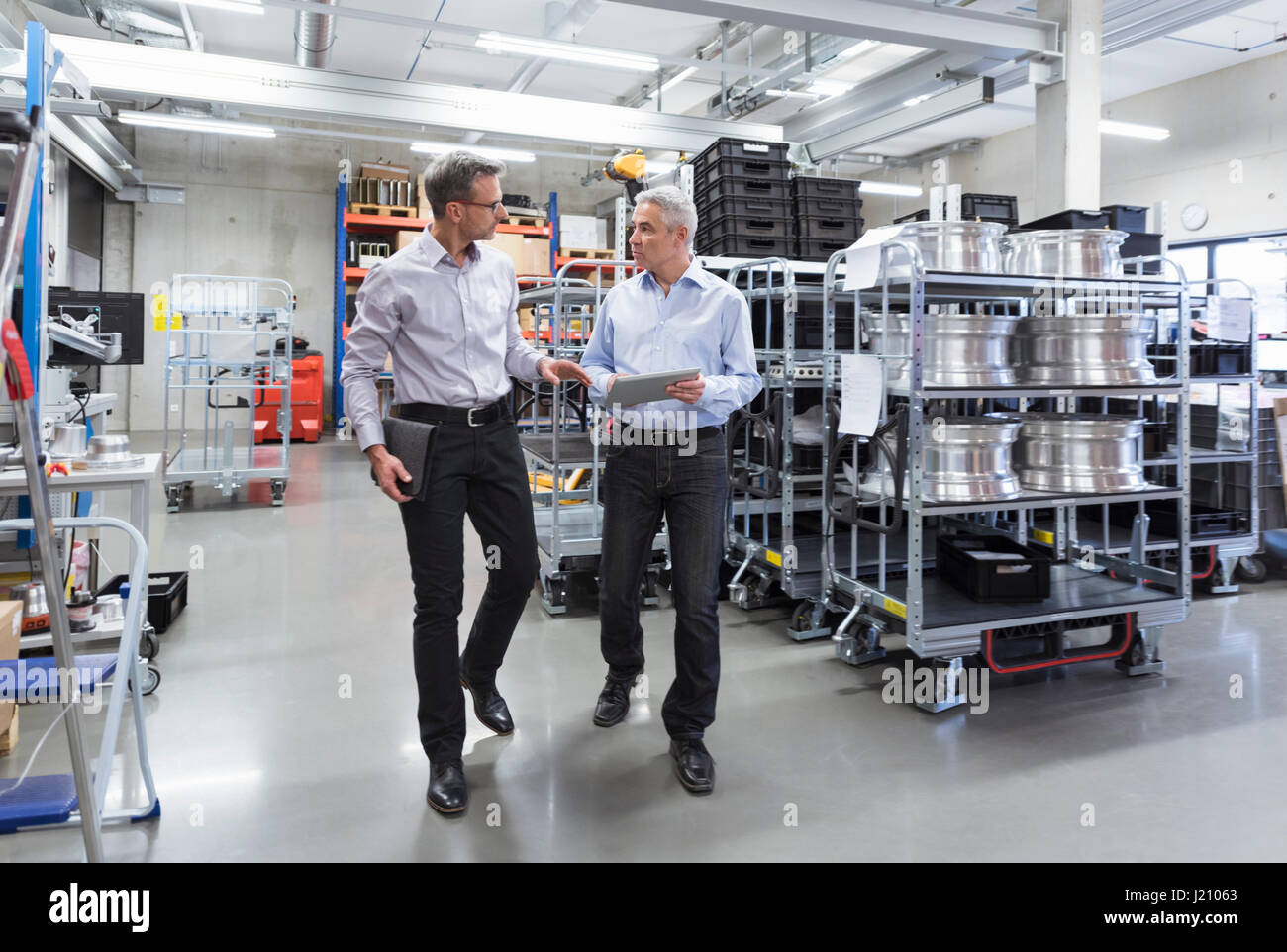 Two businessmen walking in factory hall Stock Photo - Alamy