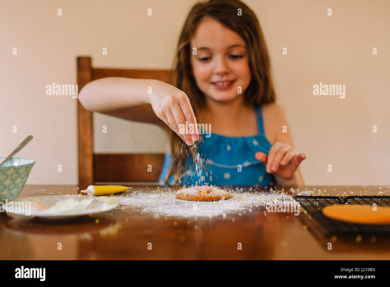 Girl decorating biscuits at home Stock Photo