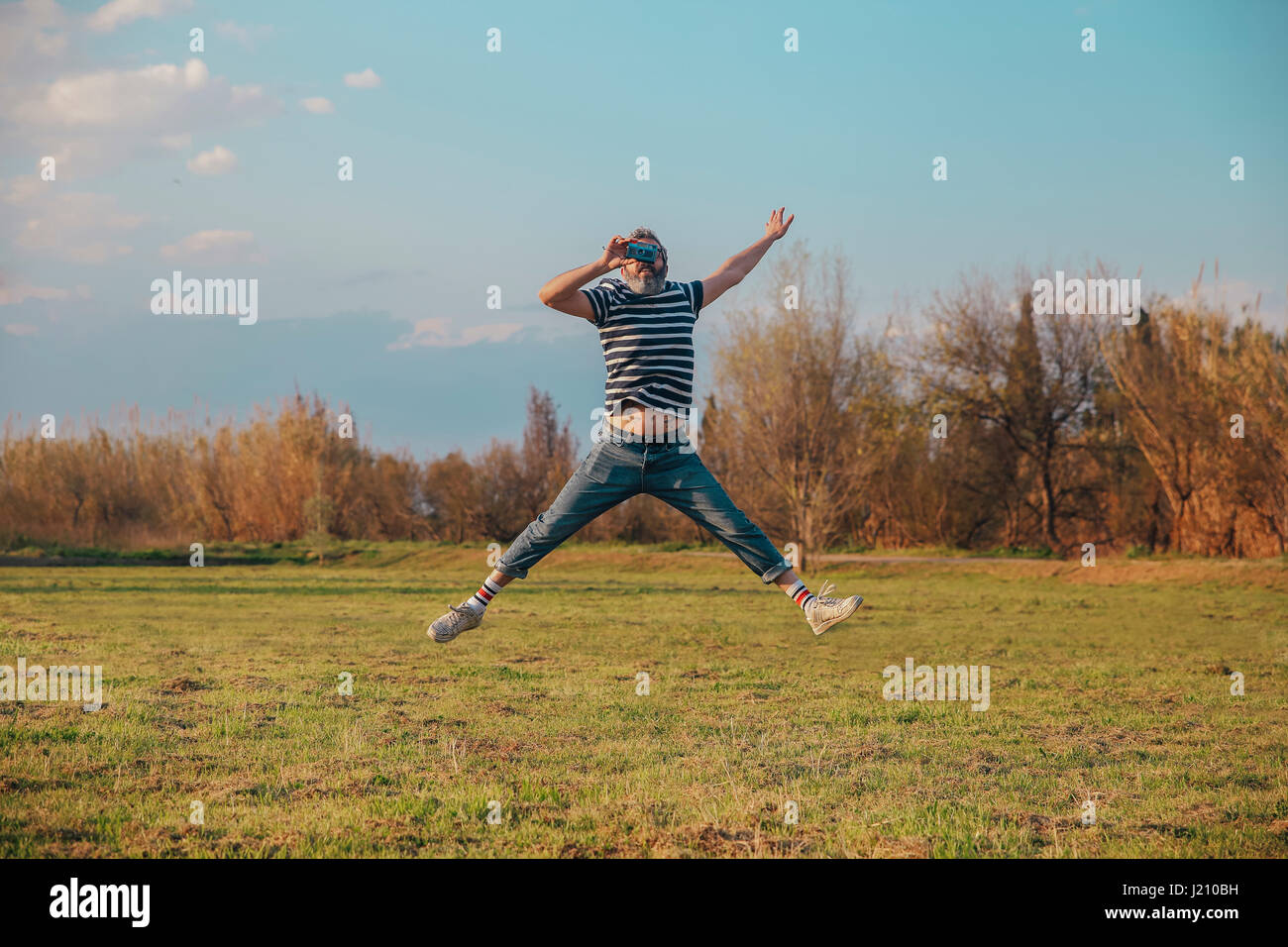 Man jumping in the air while taking photo with vintage camera Stock Photo
