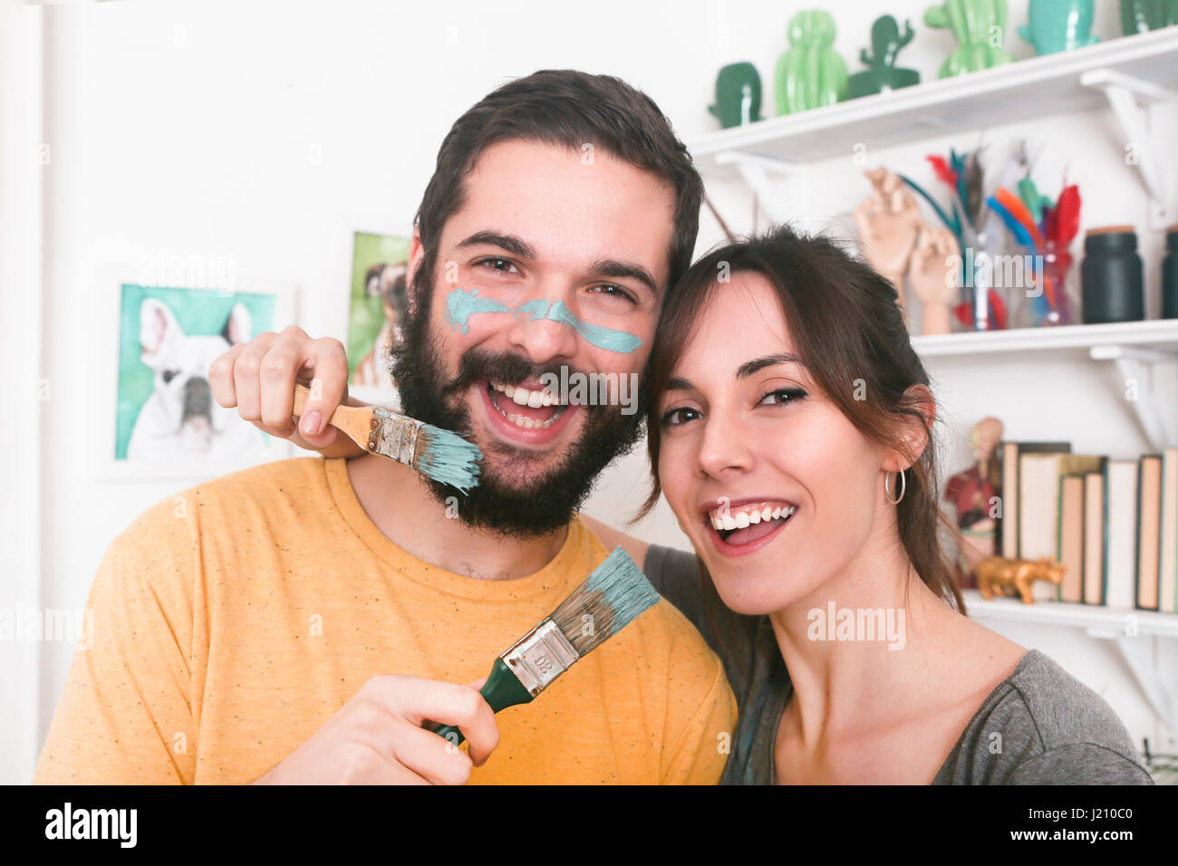 Portrait of happy young couple holding paintbrushes Stock Photo