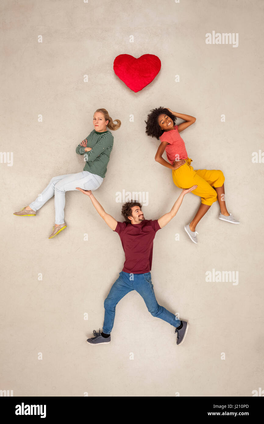 Man balancing two women on his hands, not making a decision Stock Photo