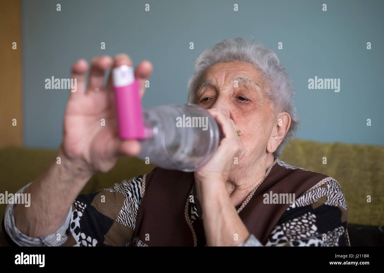 Senior woman using inhaler at home Stock Photo