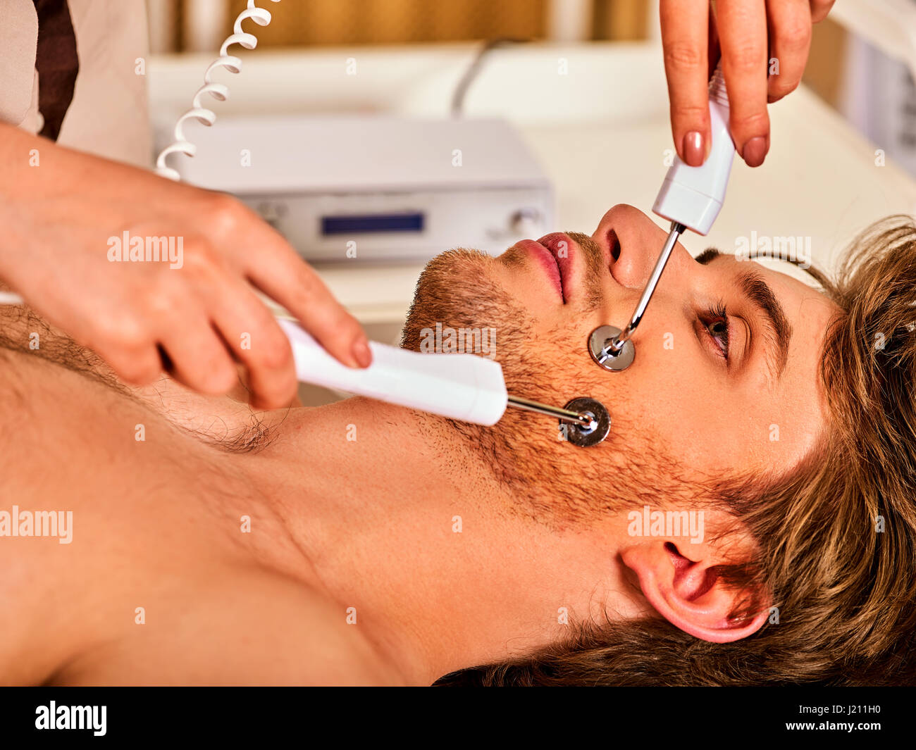 Facial massage at beauty salon. Electric stimulation woman skin care. Stock Photo