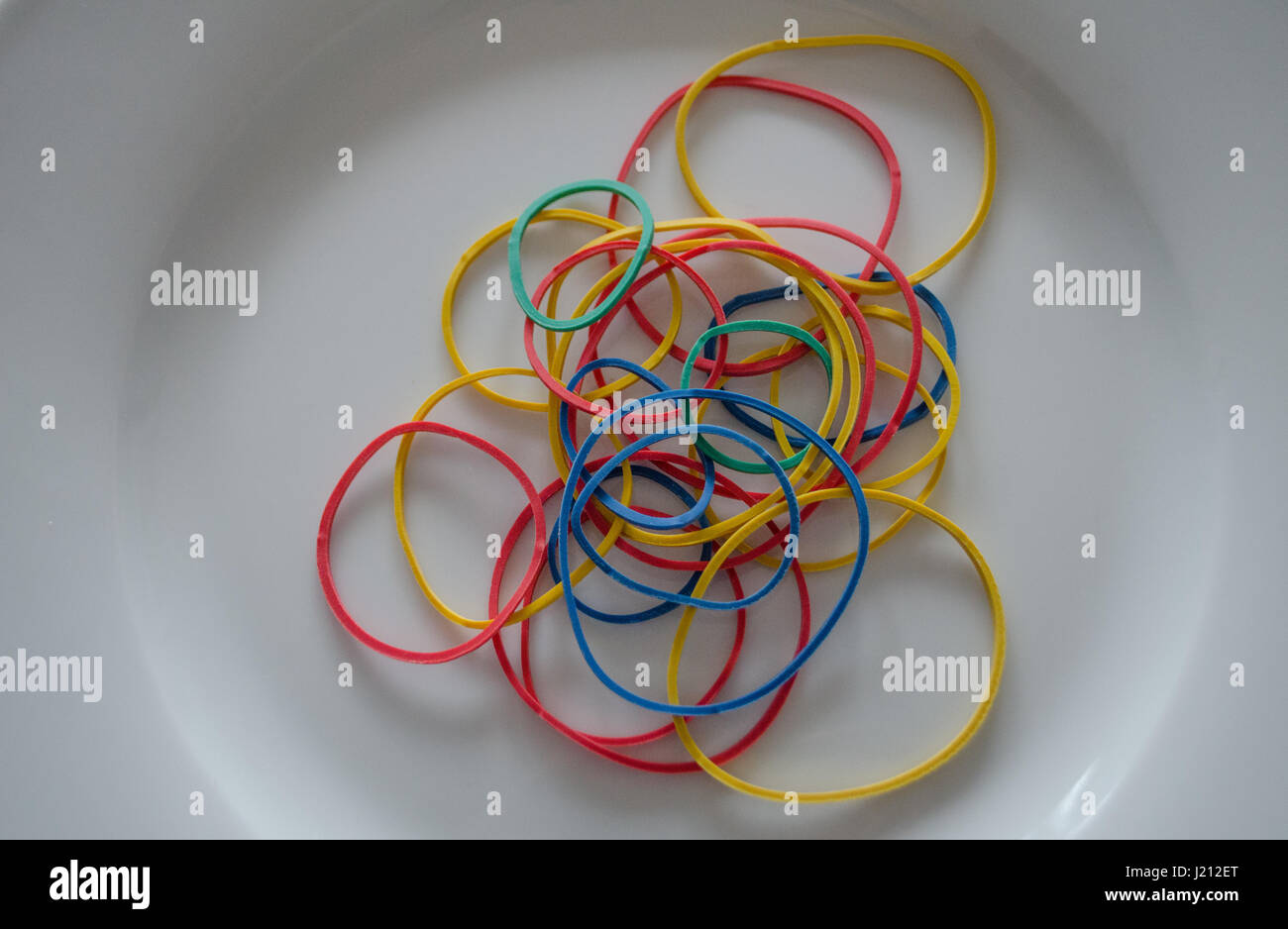 Multicolored rubber bands on white plate close up Stock Photo