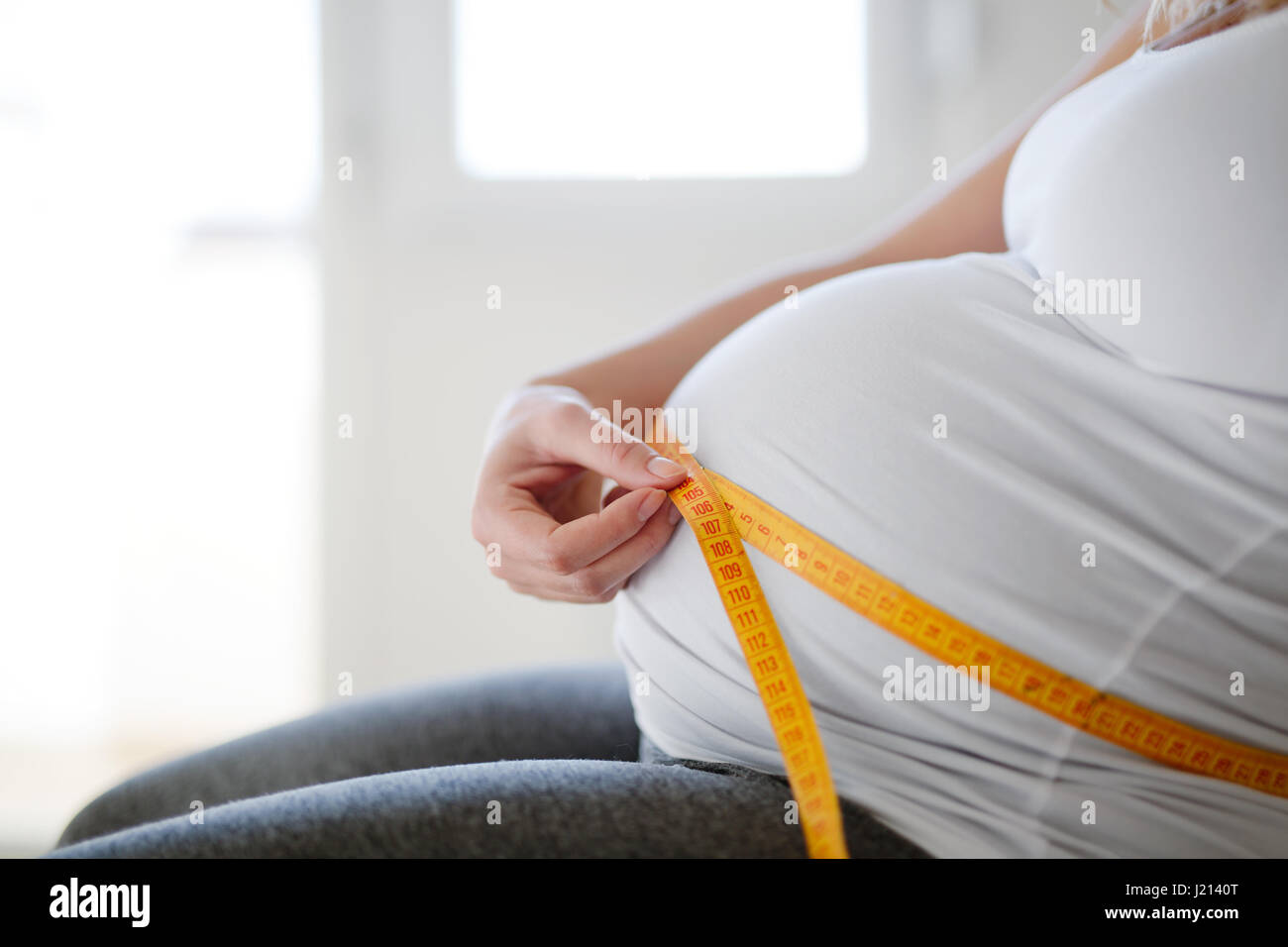 Beautiful expectant pregnant woman measuring belly growth Stock Photo