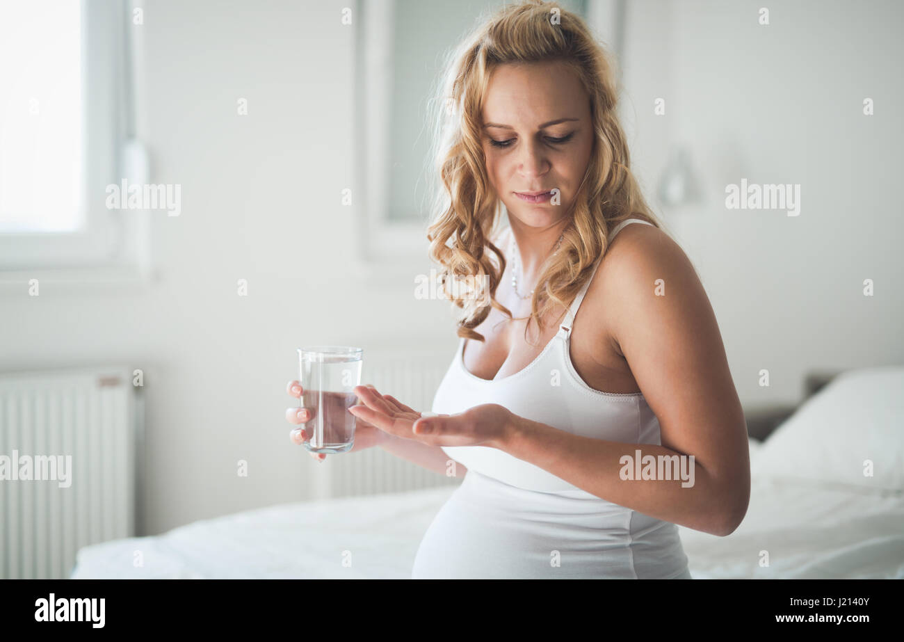 Beautiful pregnant woman taking pills for morning nausea Stock Photo