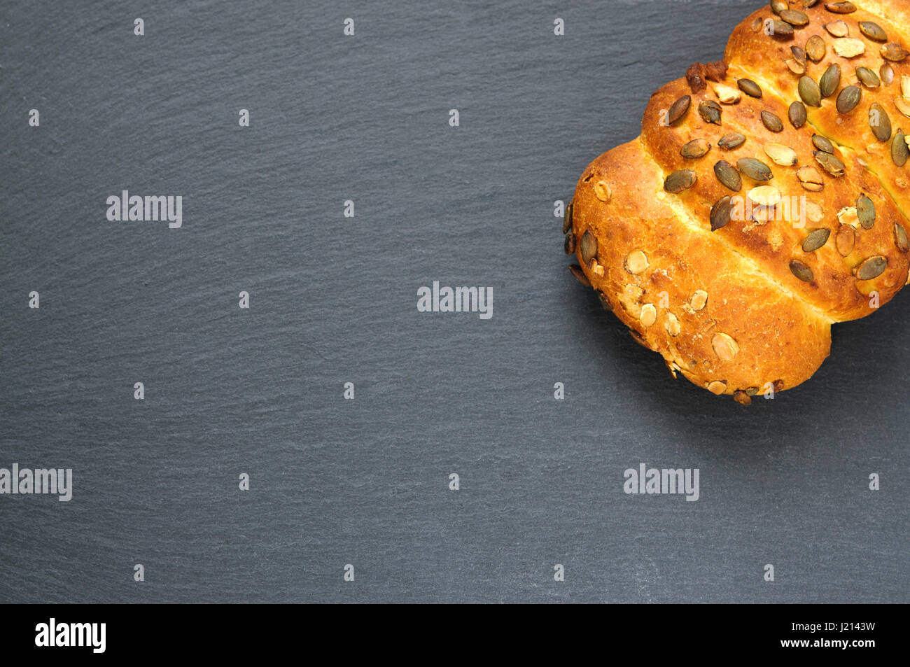 Top view of bread loaf with pumpkin seeds on black slate stone board Stock Photo