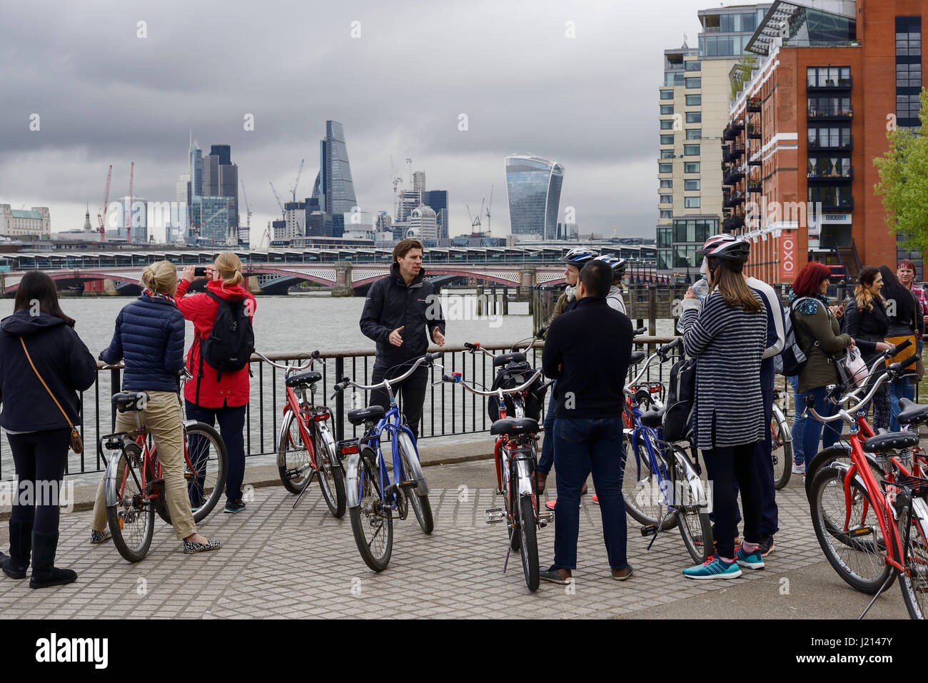 Tourists on a cycling tour along the south bank of the River Thames in London Stock Photo