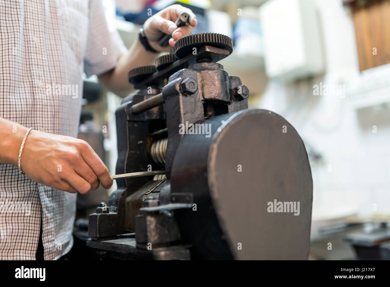 Goldsmith using machine to make metal thinner Stock Photo