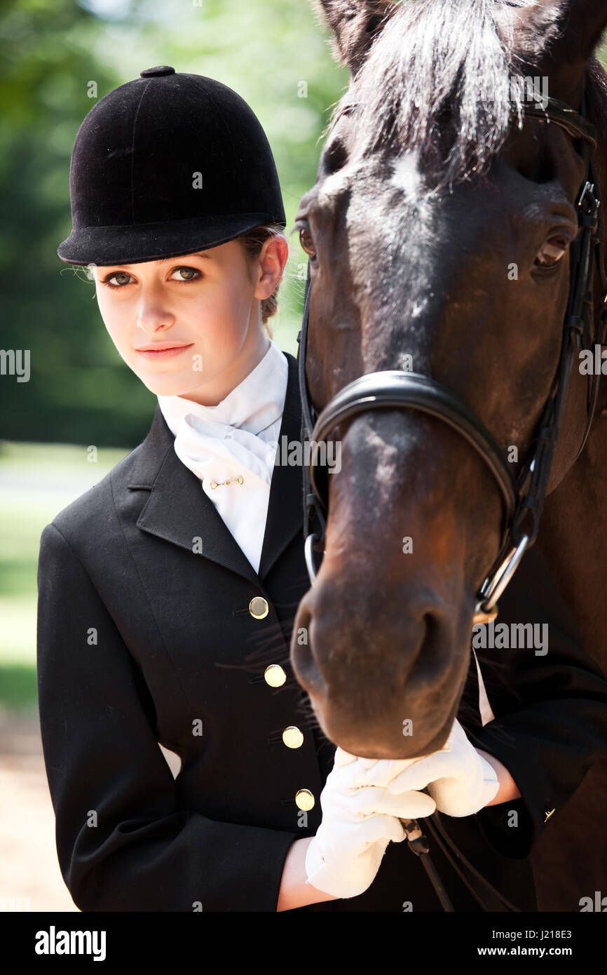 A caucasian girl getting ready for a horseback riding posing with her