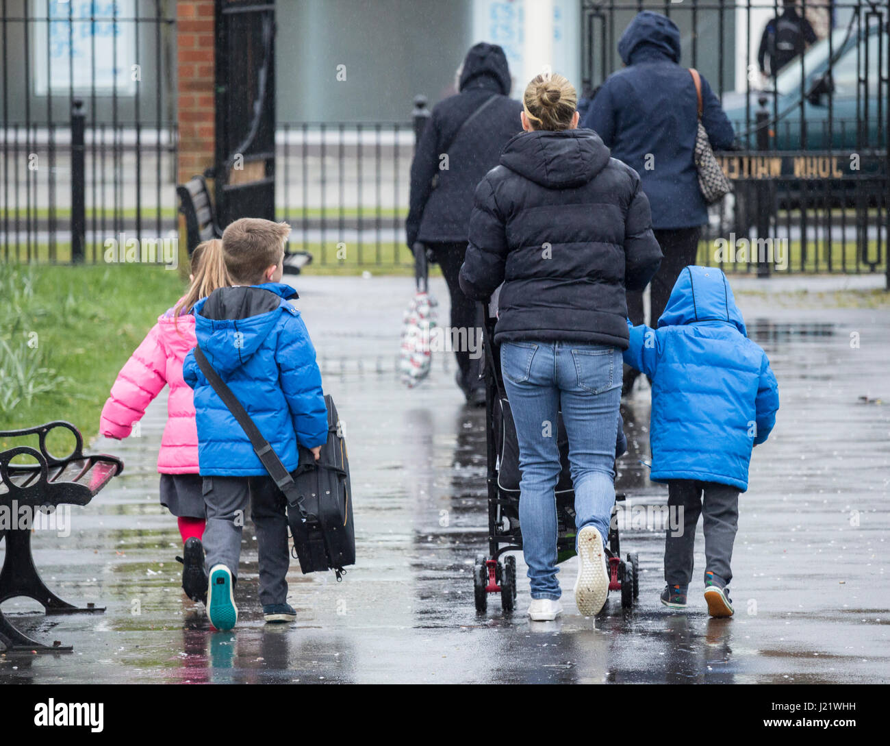 Back to school. Children heading to school in the rain. UK Stock Photo