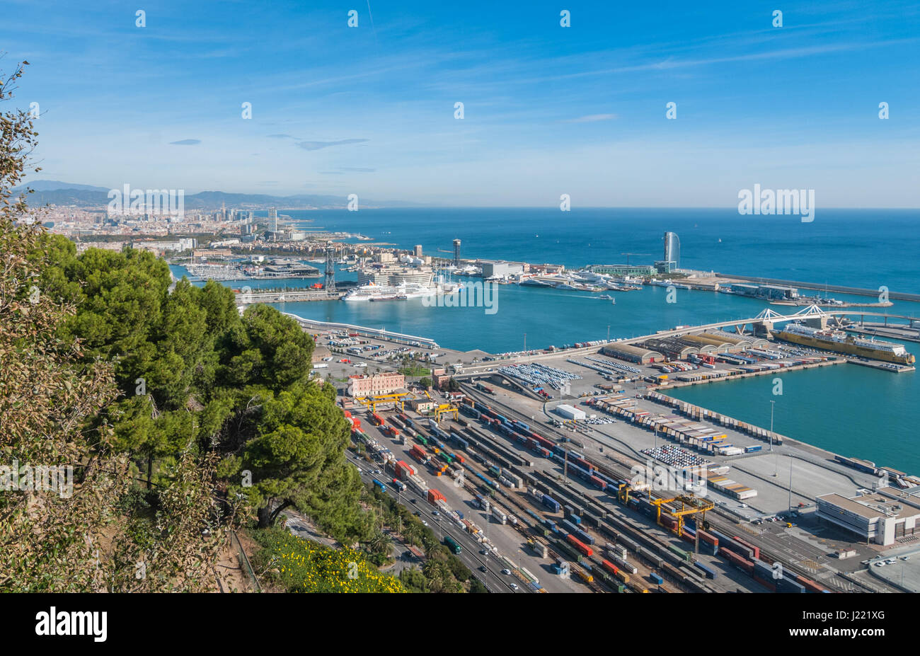 Bright sunny day on the industrial shipping & transport hub & railyard in Barcelona.  Modern cityscape & coastline of Spain. Stock Photo