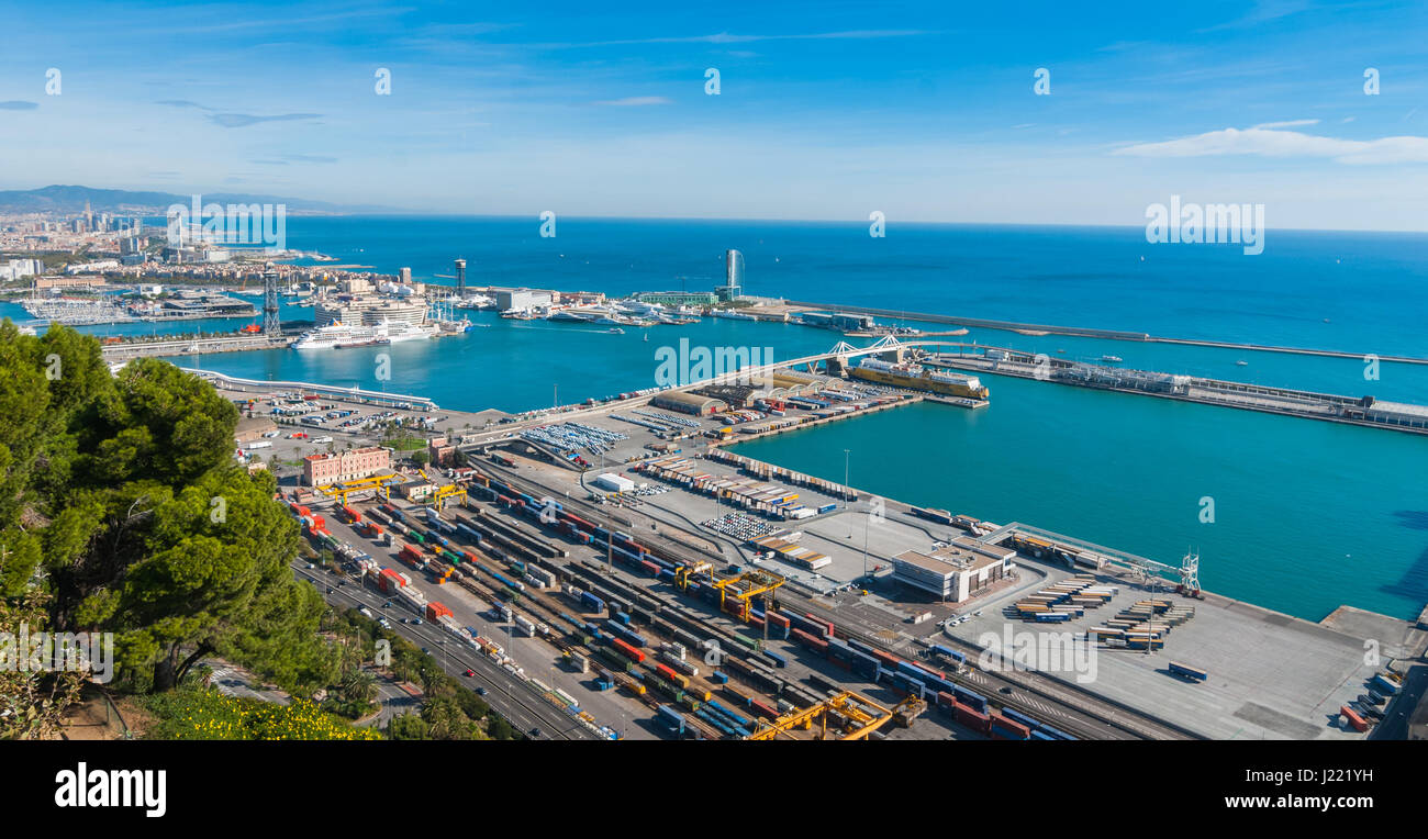 Bright sunny day on the industrial shipping & transport hub & railyard in Barcelona.  Modern cityscape & coastline of Spain. Stock Photo