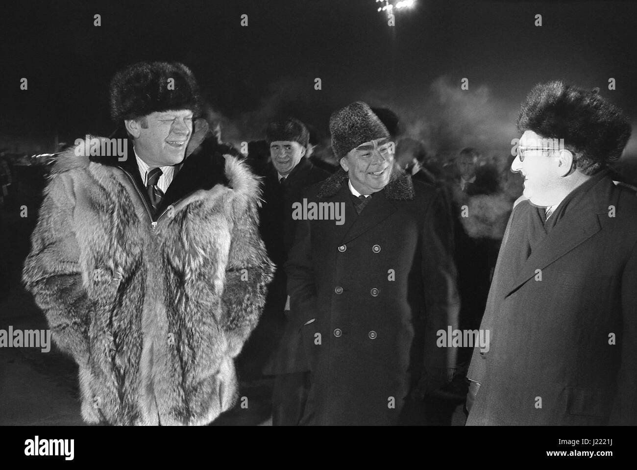U.S President Gerald Ford wearing a Russian fur hat and wolfskin coat chats with Soviet General Secretary Leonid Brezhnev, center and Secretary of State Henry Kissinger at Vozdvizhenka Airbase before departure November 24, 1974 in Vladivostok, Russia, USSR. Ford is departing at the conclusion of a two-day summit on Arms Control. Stock Photo