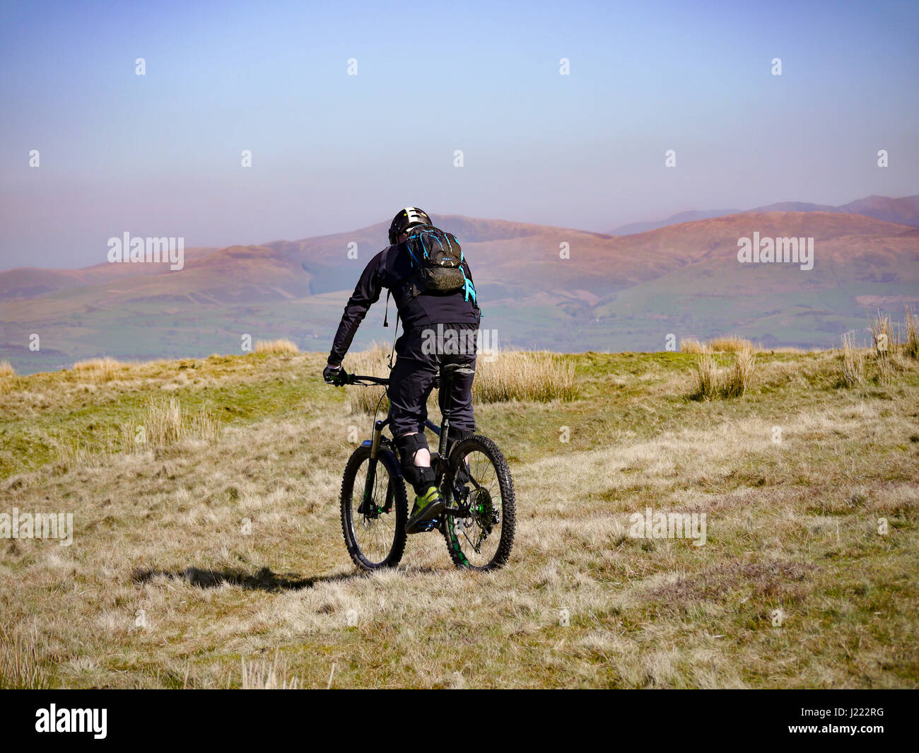 A mountain biker rides along top of Dent fell in the Lake district, Cumbria, England Stock Photo