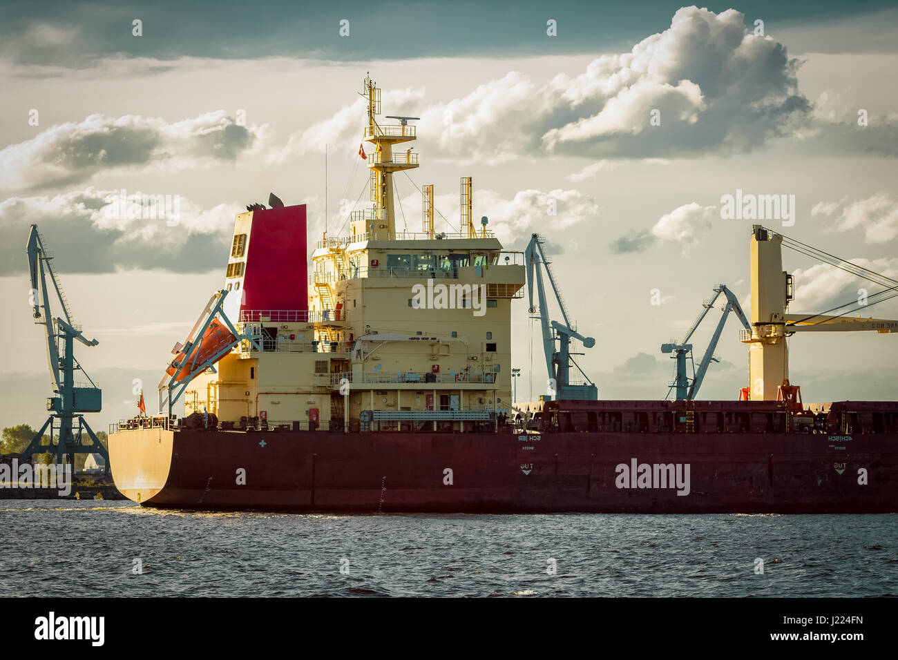 Red cargo ship's stern against port cranes Stock Photo - Alamy