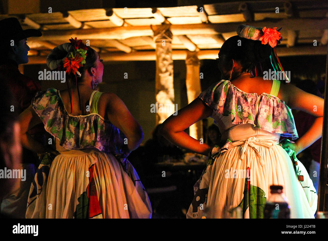 beautiful Mexican women in traditional dress, their hair up in buns and tied with ribbons, laughing together before an evening performance Stock Photo
