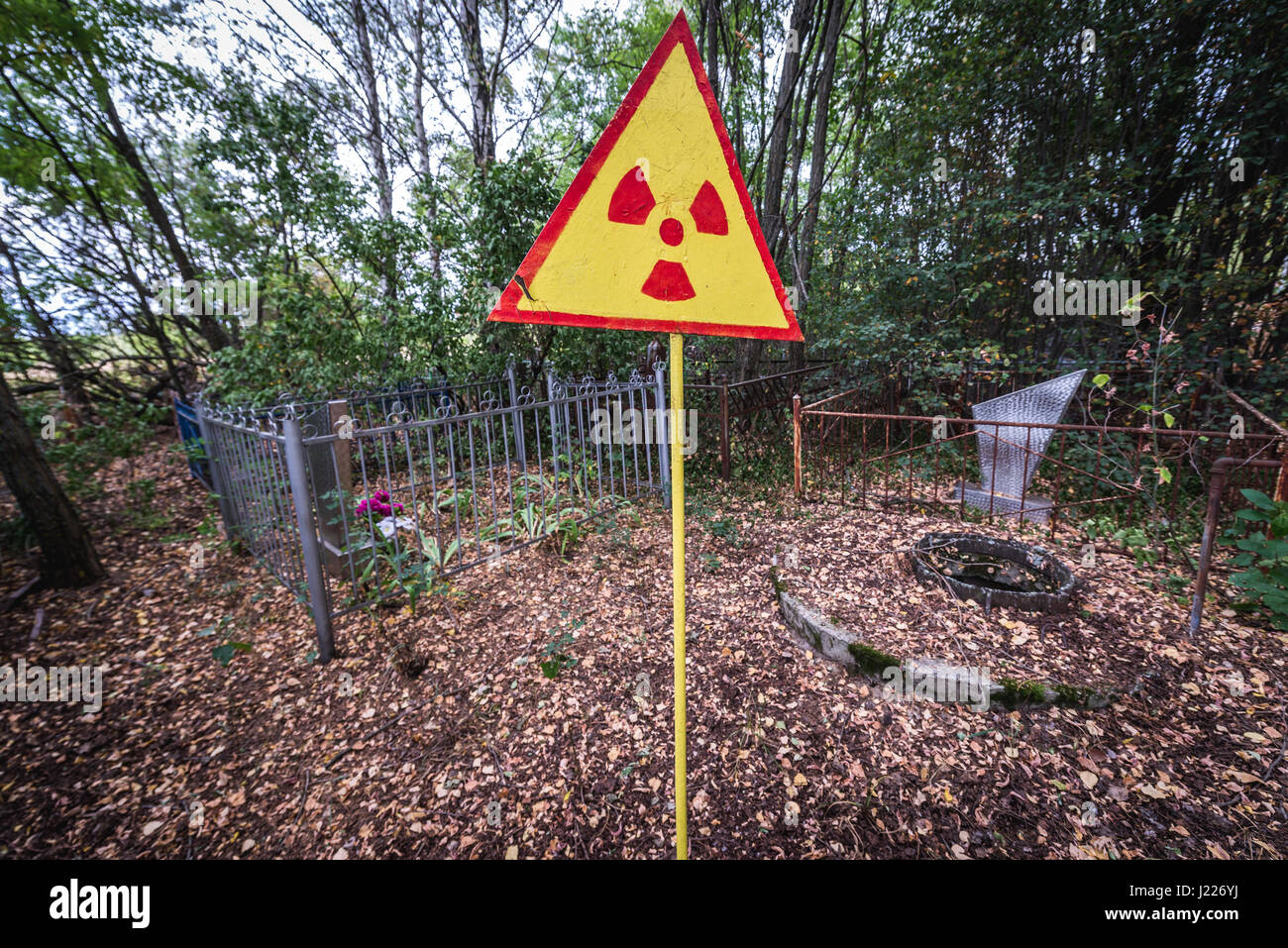 Ionising radiation warning sign on a cemetery in Pripyat ghost city of Chernobyl Nuclear Power Plant Zone of Alienation in Ukraine Stock Photo
