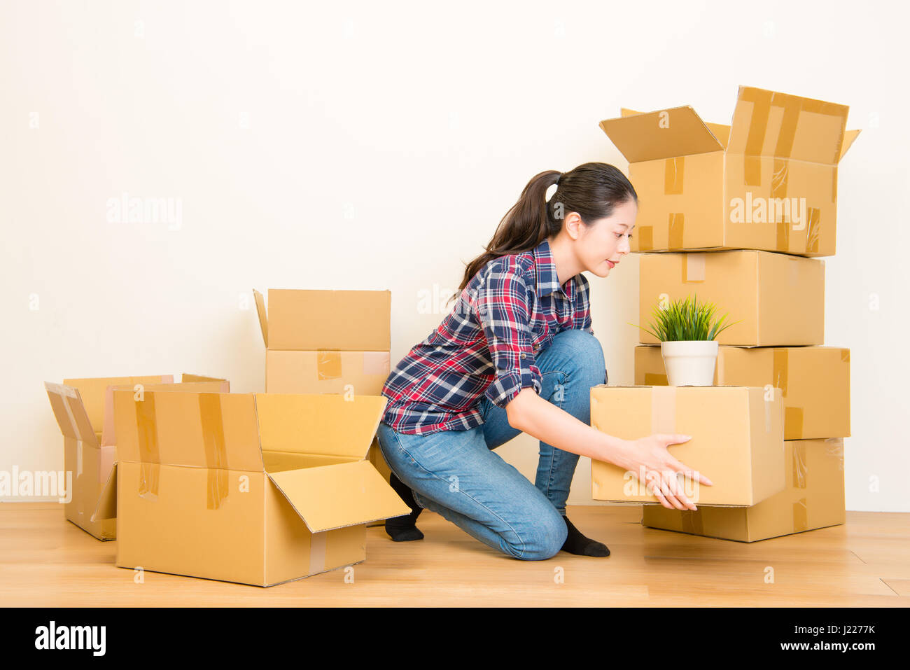 Woman packing and unpacking belongings in a carton box when moving home