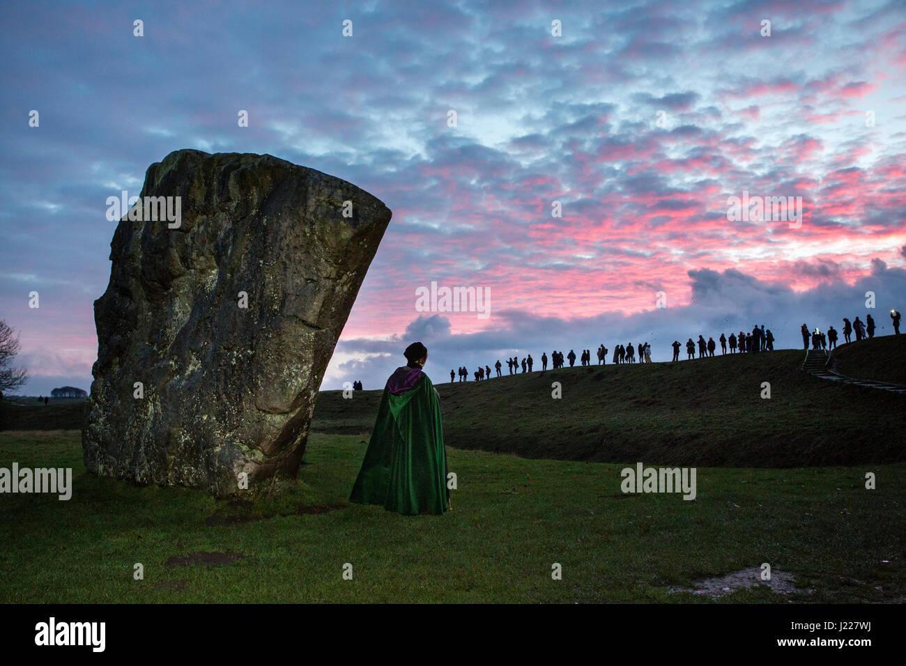 People gather in the mist and grey overcast weather at Avebury stone circle to watch the rising of the sun on the day of the winter solstice, the shortest day of the year. Stock Photo