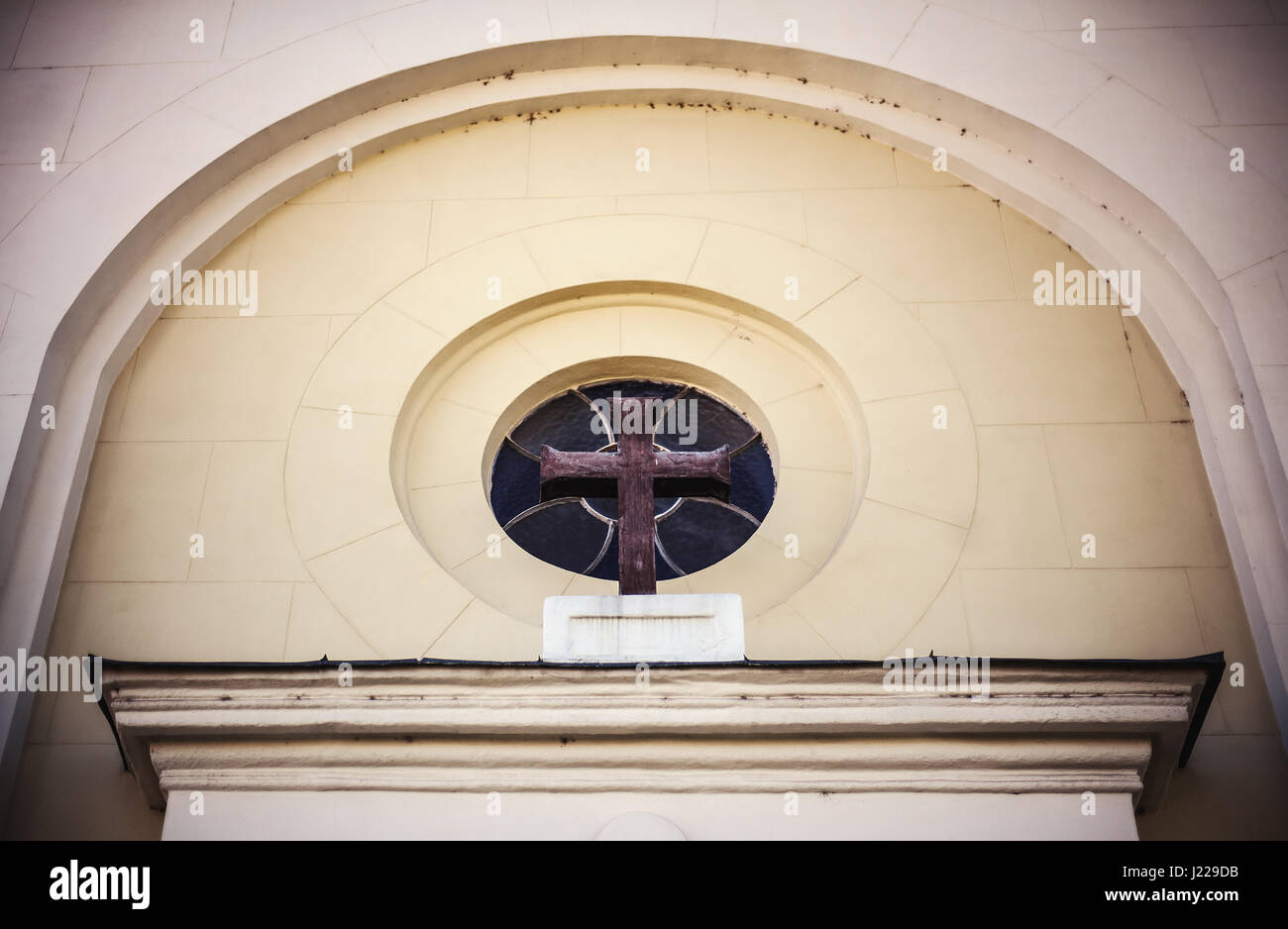 Look above the entrance of a church, wooden cross and wall details. Stock Photo