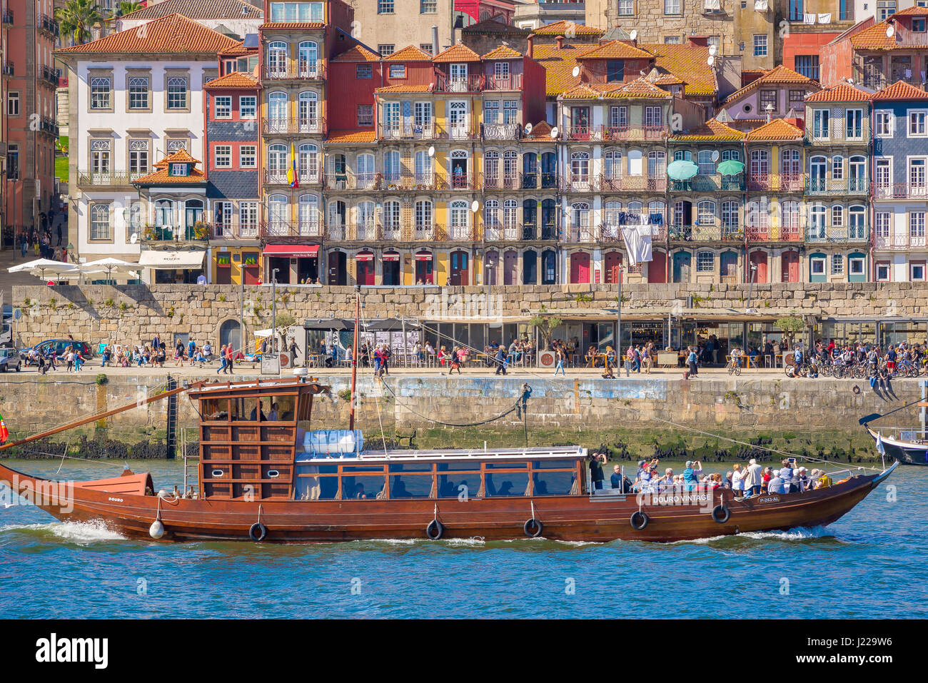 Porto Portugal Ribeira, on the Douro River a cruise boat carrying tourists sails past historic buildings sited along the Ribeira waterfront in Porto. Stock Photo